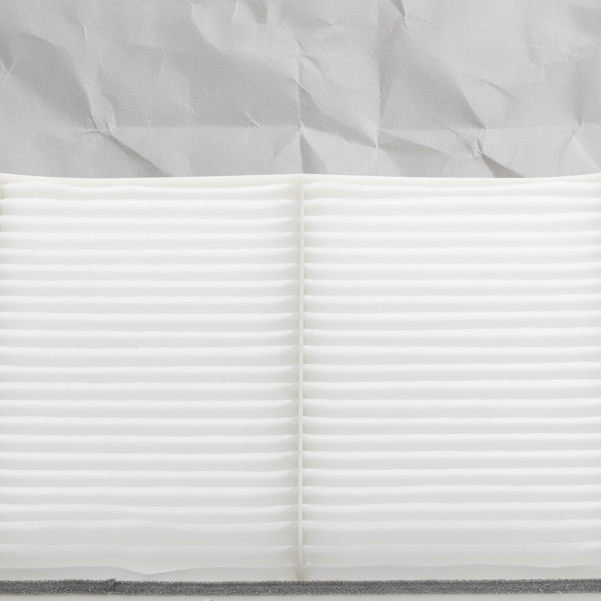 Top macro crop of Mazda CX-9 cabin air filter on light grey wrinkled kraft paper