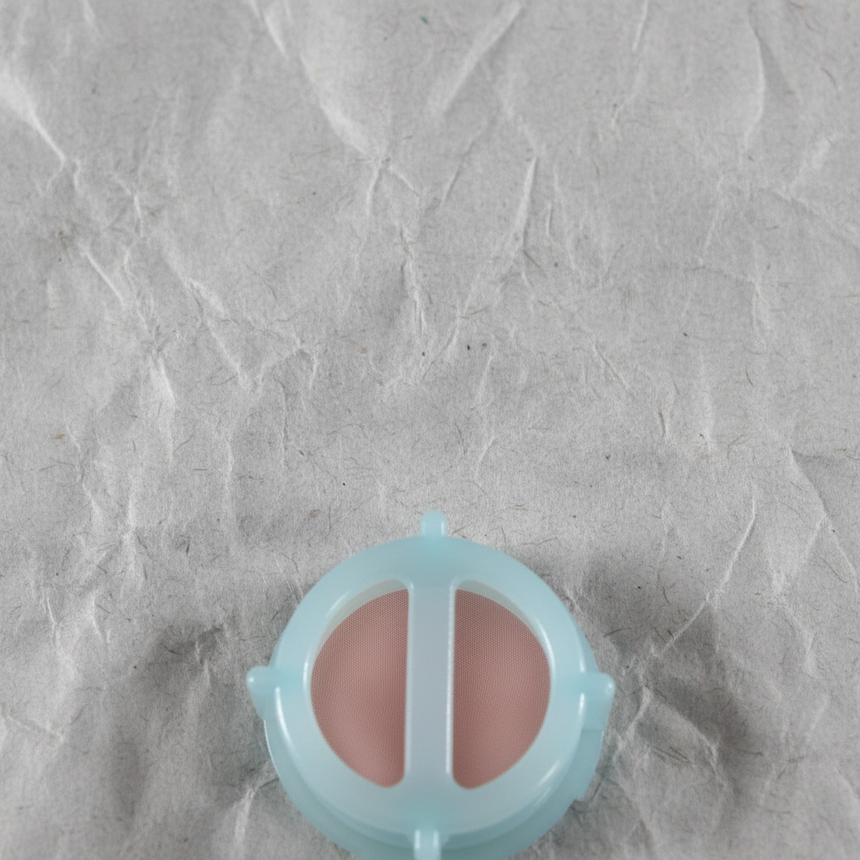 Top macro crop of brake master cylinder reservoir strainer on light grey wrinkled kraft paper