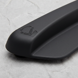 Lower-middle macro crop of seat back recliner handle on light grey wrinkled kraft paper