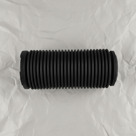 Full view of front suspension strut dust cover on light grey wrinkled kraft paper