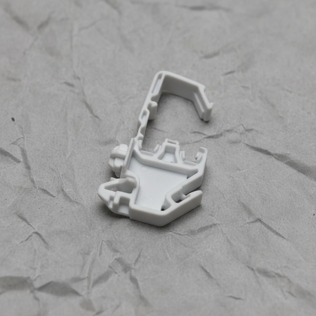Upper-middle macro crop of torsion spring clip on light grey wrinkled kraft paper background