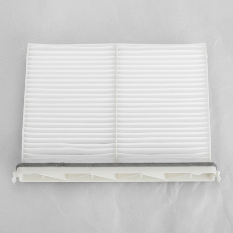 Middle macro crop of Mazda CX-9 cabin air filter on light grey wrinkled kraft paper