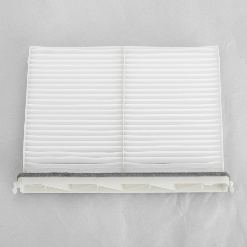 Middle macro crop of Mazda CX-9 cabin air filter on light grey wrinkled kraft paper
