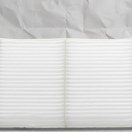 Top macro crop of Mazda CX-9 cabin air filter on light grey wrinkled kraft paper