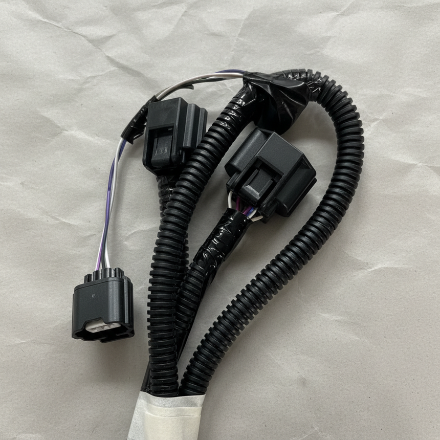 Upper-middle macro crop of rear park assist camera wiring harness on light grey wrinkled kraft paper