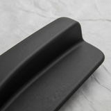 Upper-middle macro crop of seat back recliner handle on light grey wrinkled kraft paper