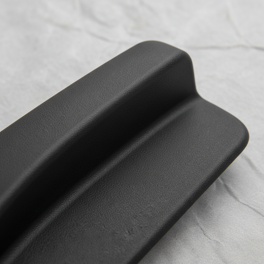 Upper-middle macro crop of seat back recliner handle on light grey wrinkled kraft paper