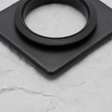Bottom macro crop of washer pump grommet on light grey wrinkled kraft paper