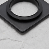 Bottom macro crop of washer pump grommet on light grey wrinkled kraft paper